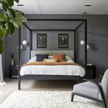 Bedroom with double bed dressed with grey bedding, wooden flooring and cream rug.  An Arts and Crafts house in North London, redesigned, pared-back and updated by Finkernagel and Ross Architects, the home of Ebbe and Afi Parsian and their twin daughters.